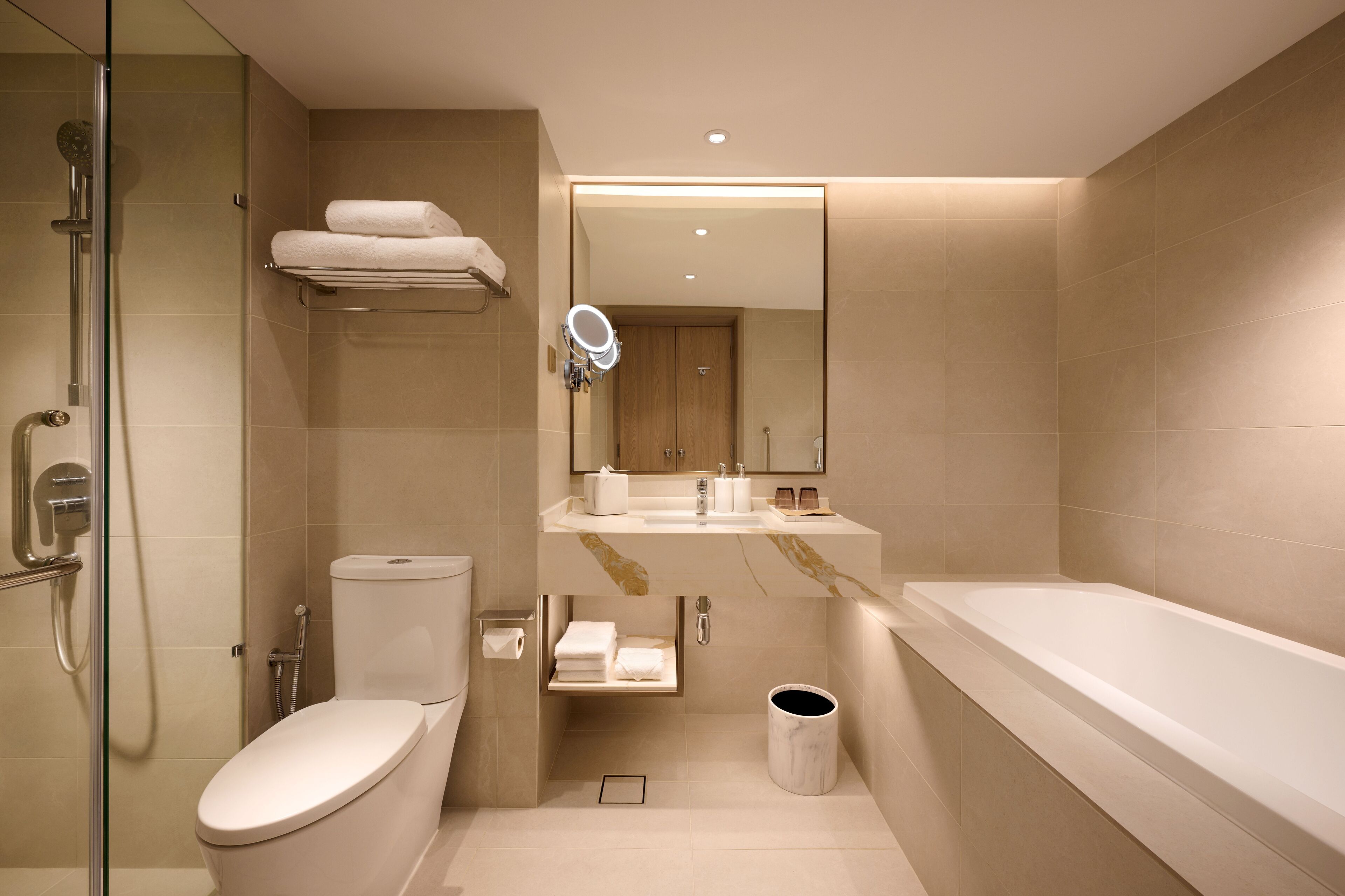 A modern bathroom with a glass-enclosed shower, a toilet, a sink with a mirror, and a bathtub.