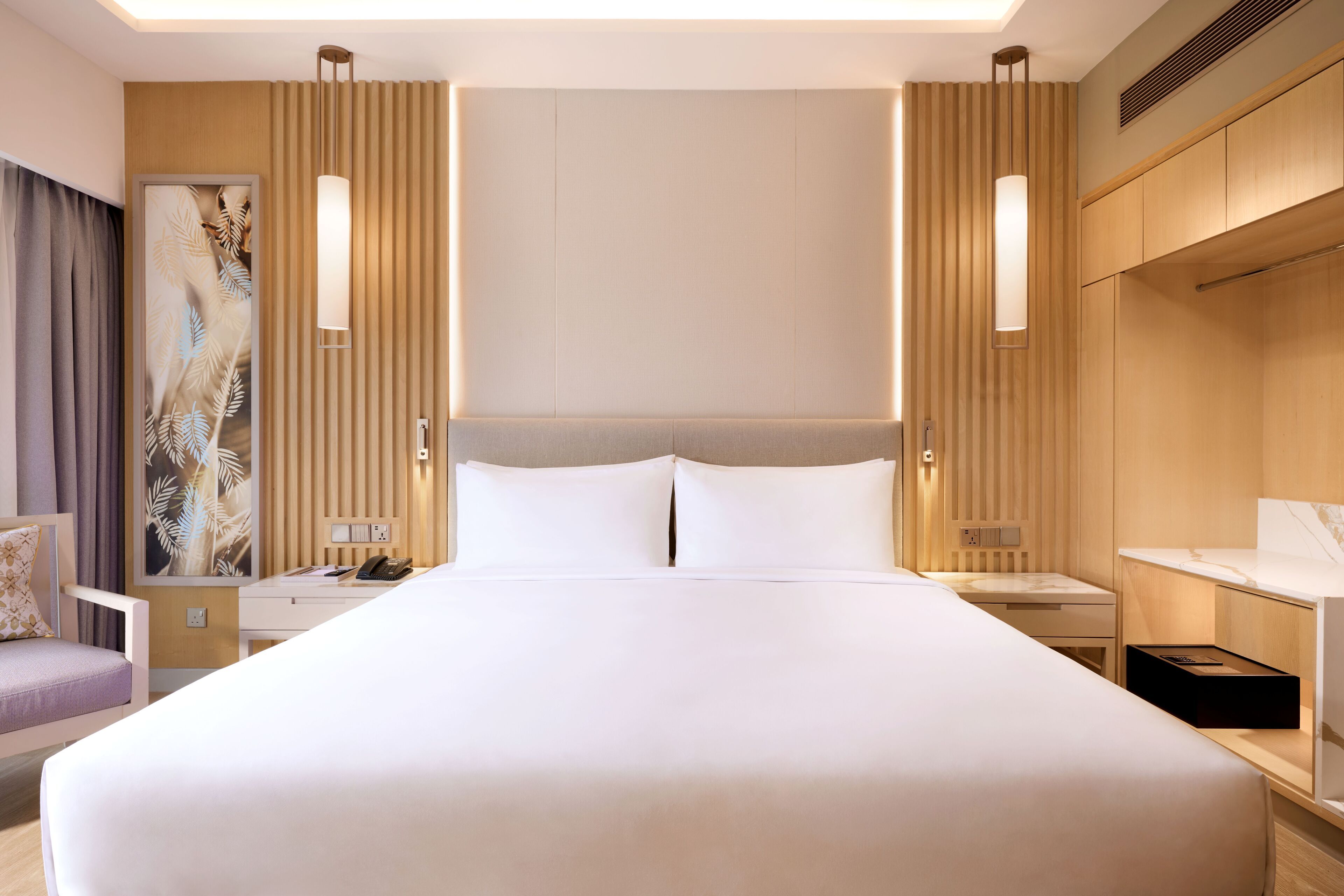 A hotel room with a large bed, bedside tables, a desk, and a chair.