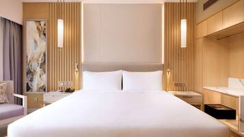 A hotel room with a large bed, bedside tables, a desk, and a chair.