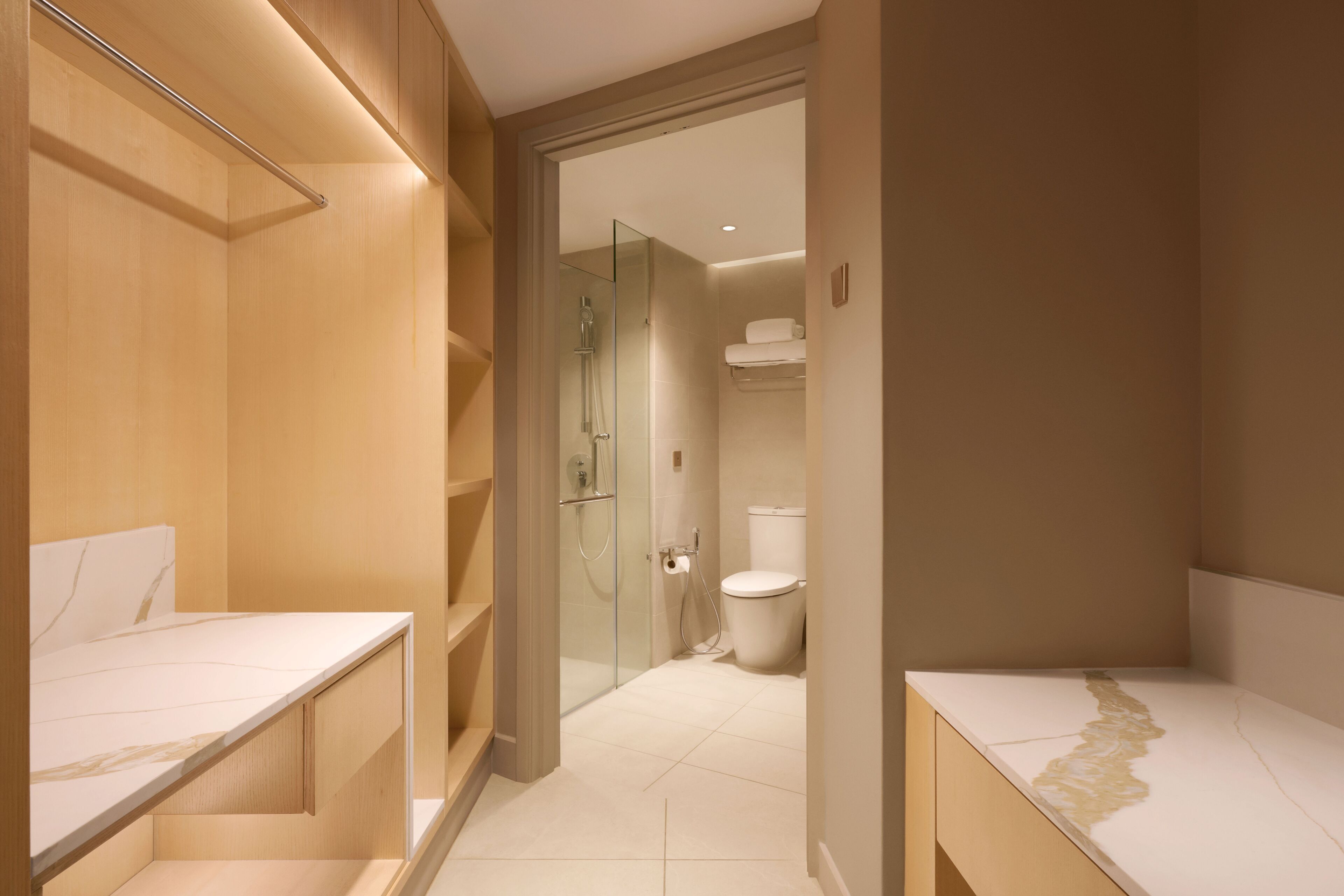 Une salle de bain moderne dotée d’une douche à parois de verre, de toilettes et d’un meuble-lavabo avec un plan de travail en marbre.