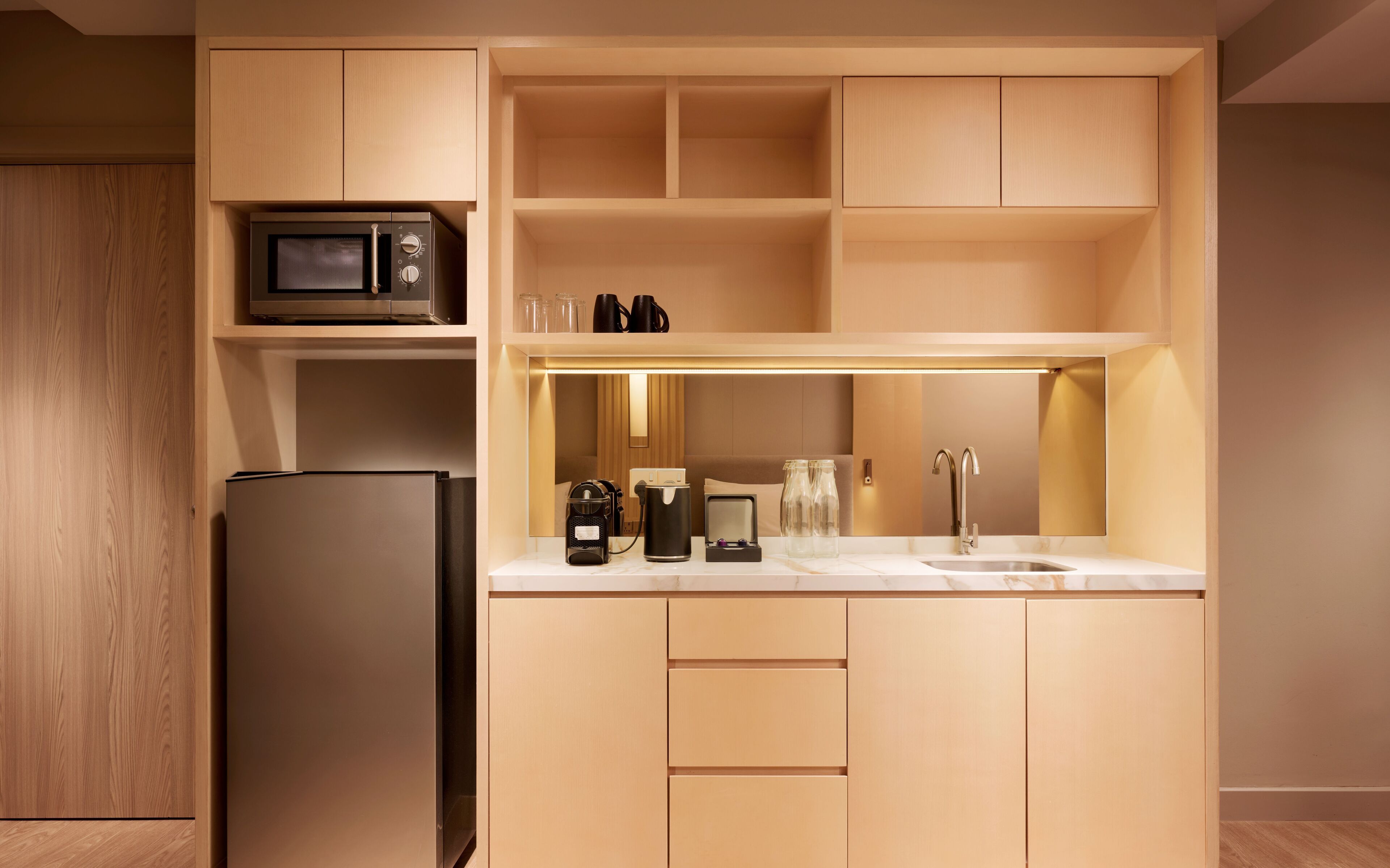 A compact kitchen with a microwave, refrigerator, coffee maker, and a sink.