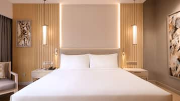A hotel room with a large bed, bedside tables, a chair, and artwork on the walls.