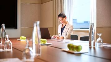 Un salón de conferencias con una computadora portátil, cristalería y manzanas verdes sobre la mesa.