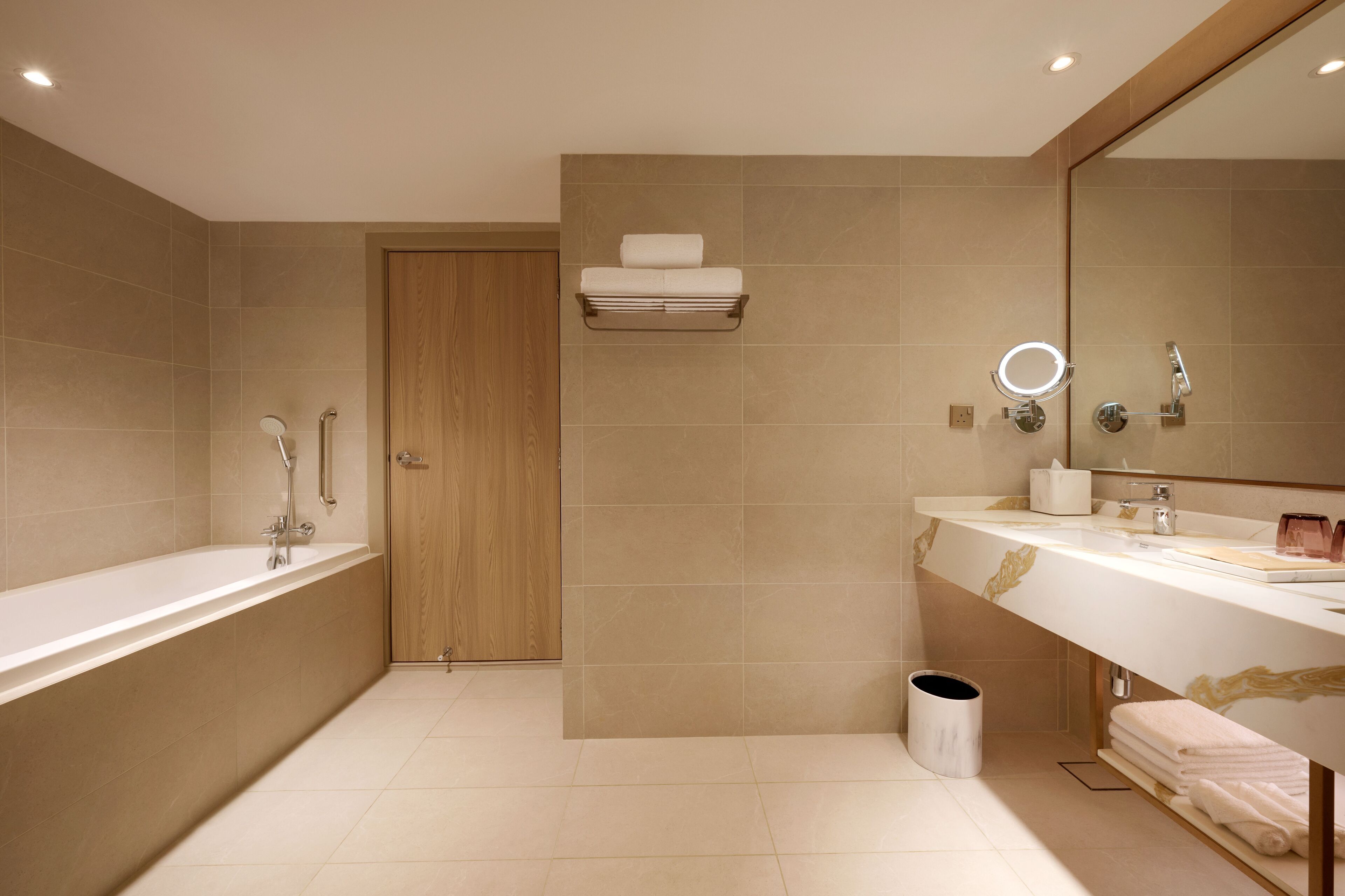 A modern bathroom with a bathtub, a vanity with a mirror, and a towel rack.