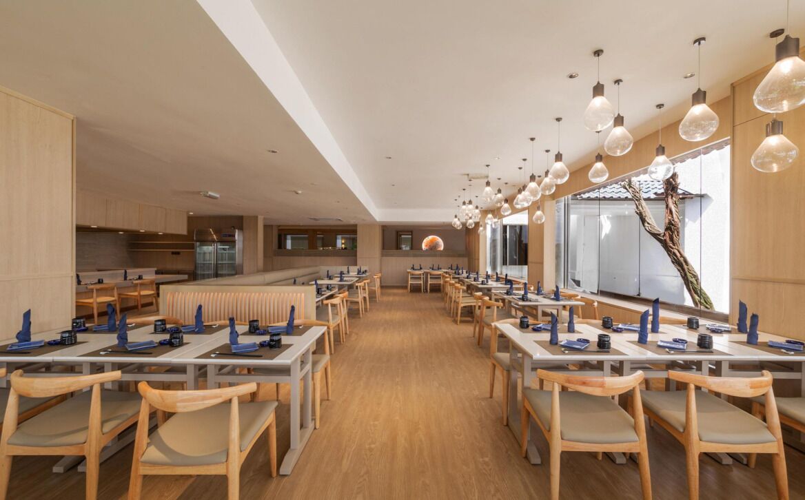 Ein geräumiges Restaurant mit langen Tischen, Holzkästen und Pendelleuchten.