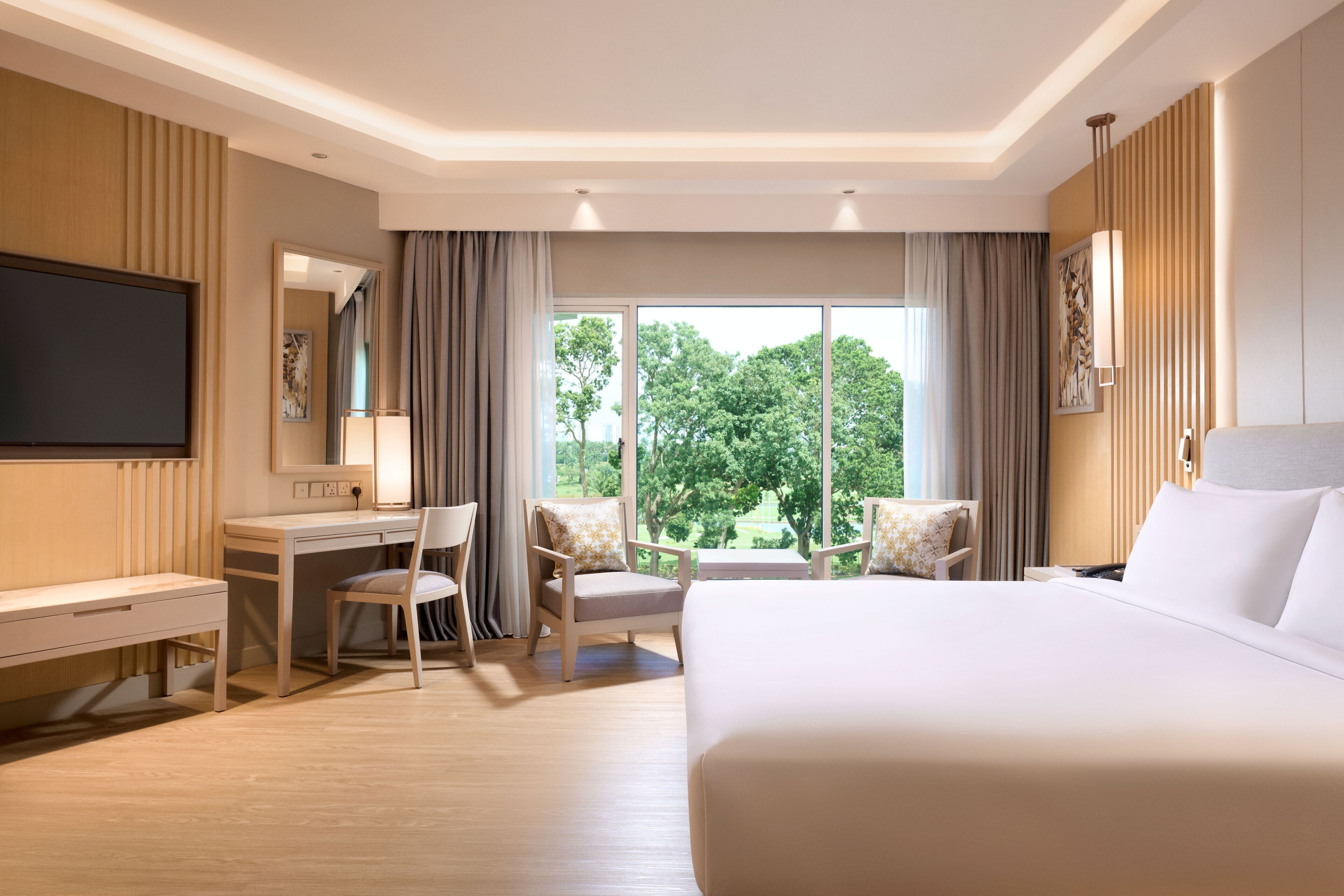 A hotel room with a large bed, a desk, a chair, and a TV.
