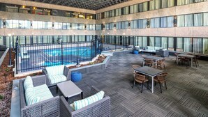 A spacious outdoor area with a pool, seating arrangements, and a covered section with tables and chairs.
