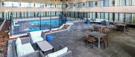 Un amplio espacio al aire libre con piscina, zonas de estar y una sección cubierta con mesas y sillas.