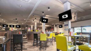 A modern restaurant interior with multiple seating areas, including high chairs and tables.