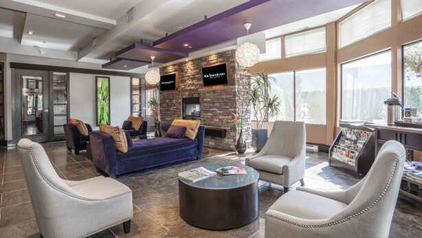 A modern lobby with a stone fireplace, comfortable seating, and large windows.