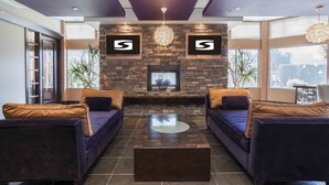 A modern living room with a stone fireplace, two sofas, a coffee table, and large windows offering a city view.