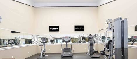 A gym with treadmills, weight machines, and a mirrored wall.