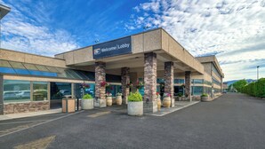 A modern hotel entrance with a 'Welcome | Lobby' sign, large windows, and outdoor planters.