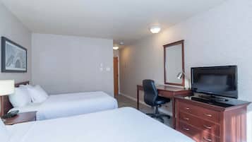 A hotel room with two beds, a desk with a TV, a chair, and a dresser.