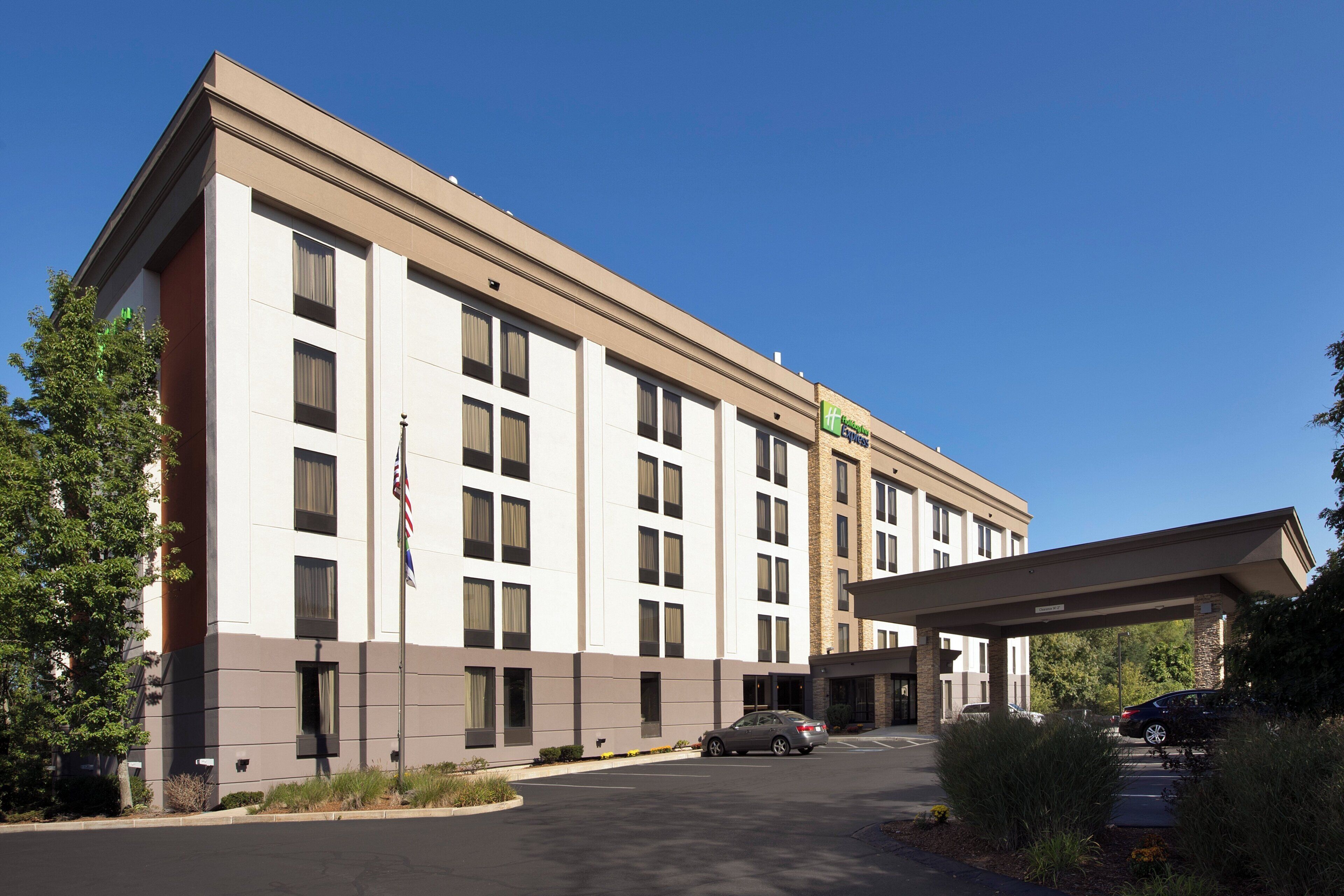 Un hôtel à plusieurs étages, doté d’une façade sobre, d’une entrée abritée et d’un parking.