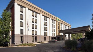A multi-story hotel with a flat facade, a covered entrance, and a parking lot. - Holiday Inn Express Andover North-Lawrence by IHG (Lawrence)