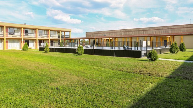 A building with a flat roof, multiple balconies, and a grassy courtyard.