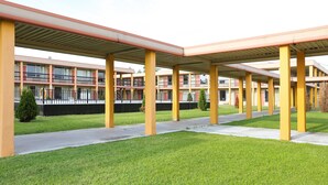 A covered outdoor area with yellow pillars and a pathway leading to a building with multiple balconies.
