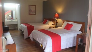 A hotel room with two beds, a desk, and a lamp.