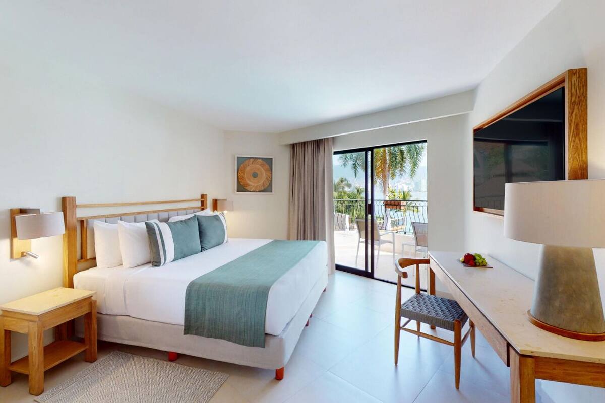Quarto de hotel moderno com cama, escrivaninha e vista para o exterior.
