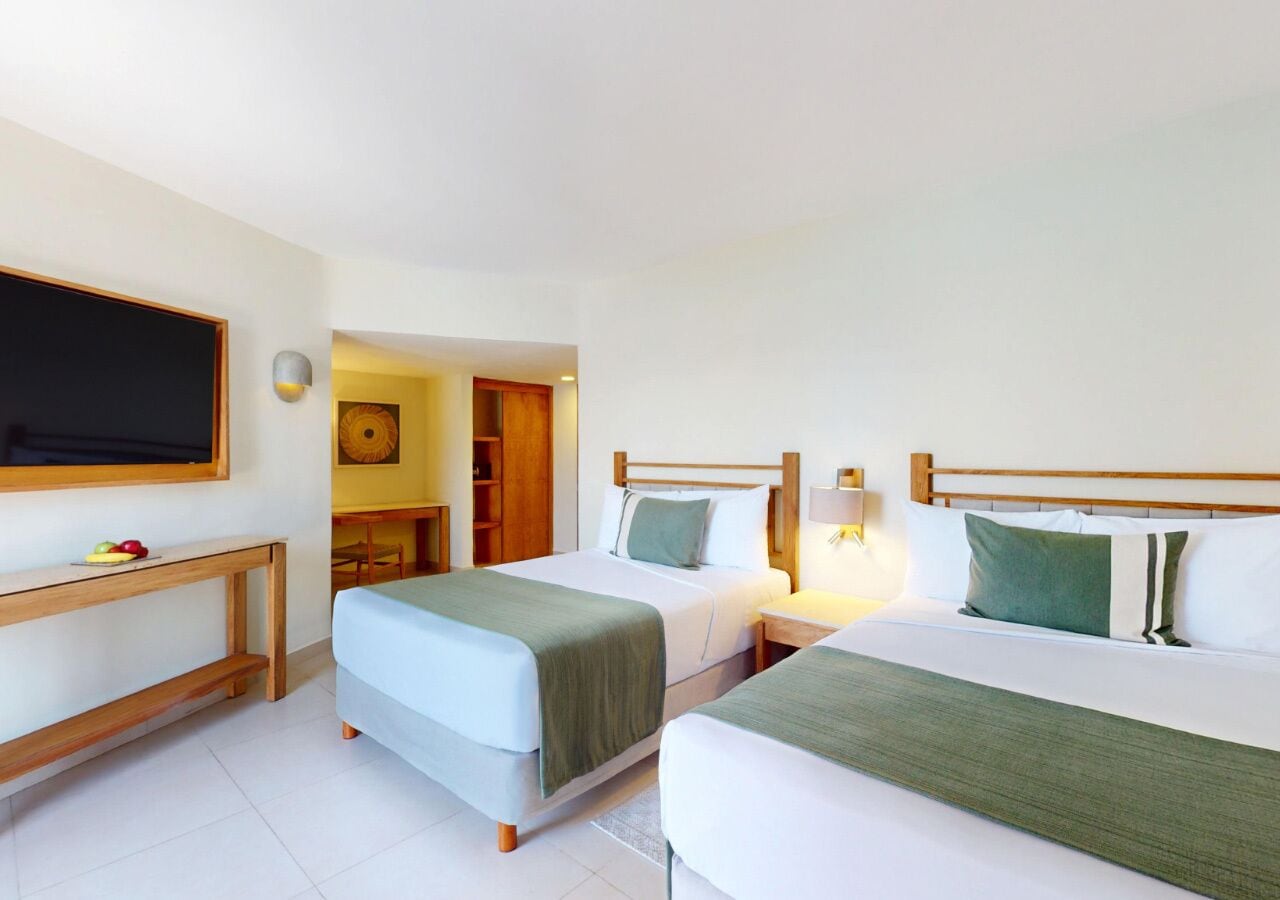 A hotel room with two beds, a desk, and a TV.