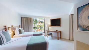 A hotel room with two beds, a desk, a chair, a TV, and a large window with a view of greenery.