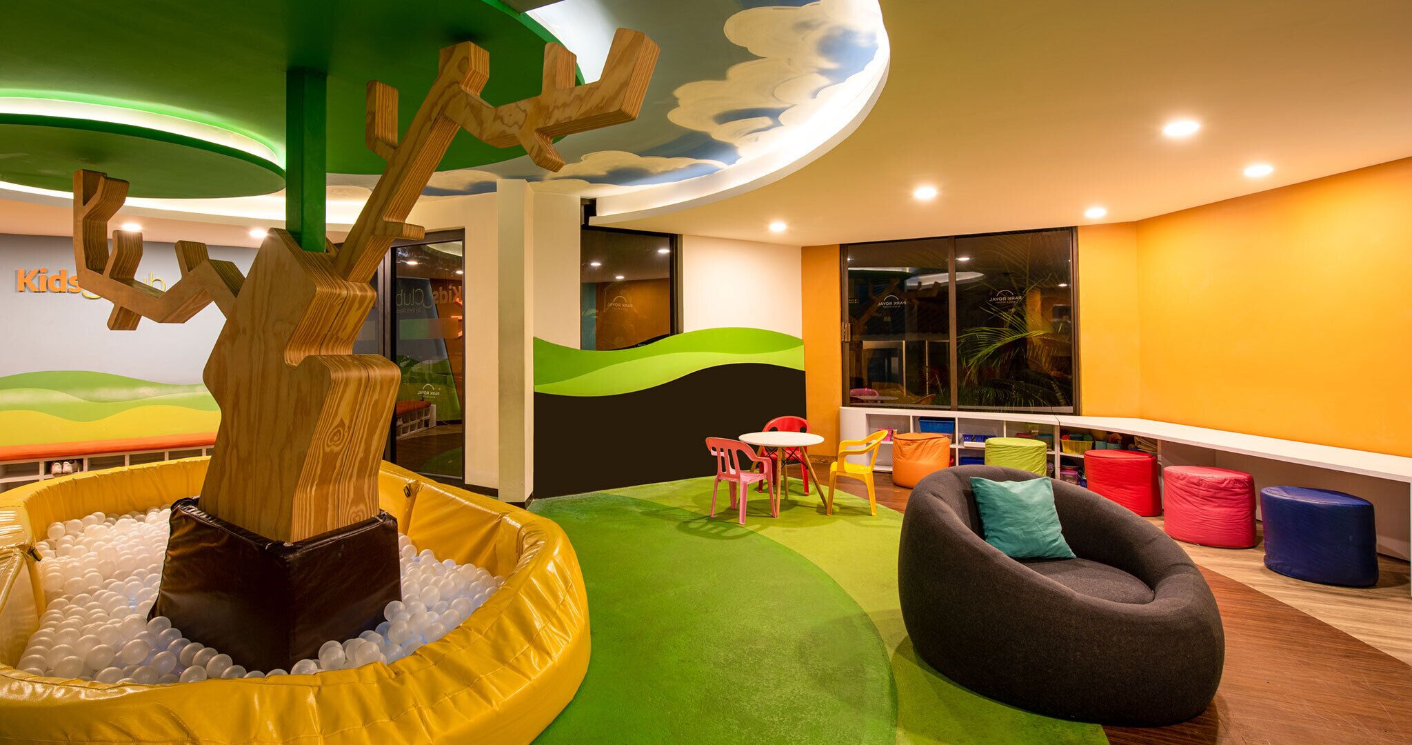 A children's play area with a ball pit, a tree sculpture, and colorful seating.