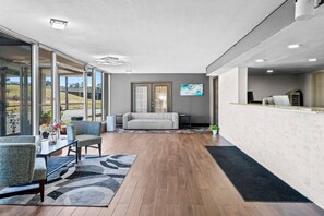 A spacious living area with a sofa, chairs, a coffee table, and a view through large glass doors. - Quality Inn Little Rock South (Little Rock)