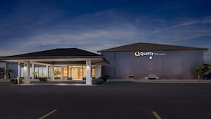 Hoteleingang mit überdachter Wartezone und einem großen Gebäude, das die Beschilderung "Quality Inn by Choice Hotels" trägt.