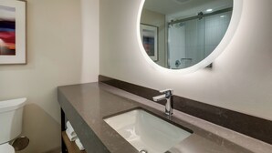 Een moderne badkamer met een marmeren wastafel, een grote spiegel en een ingelijst beeld op de muur.