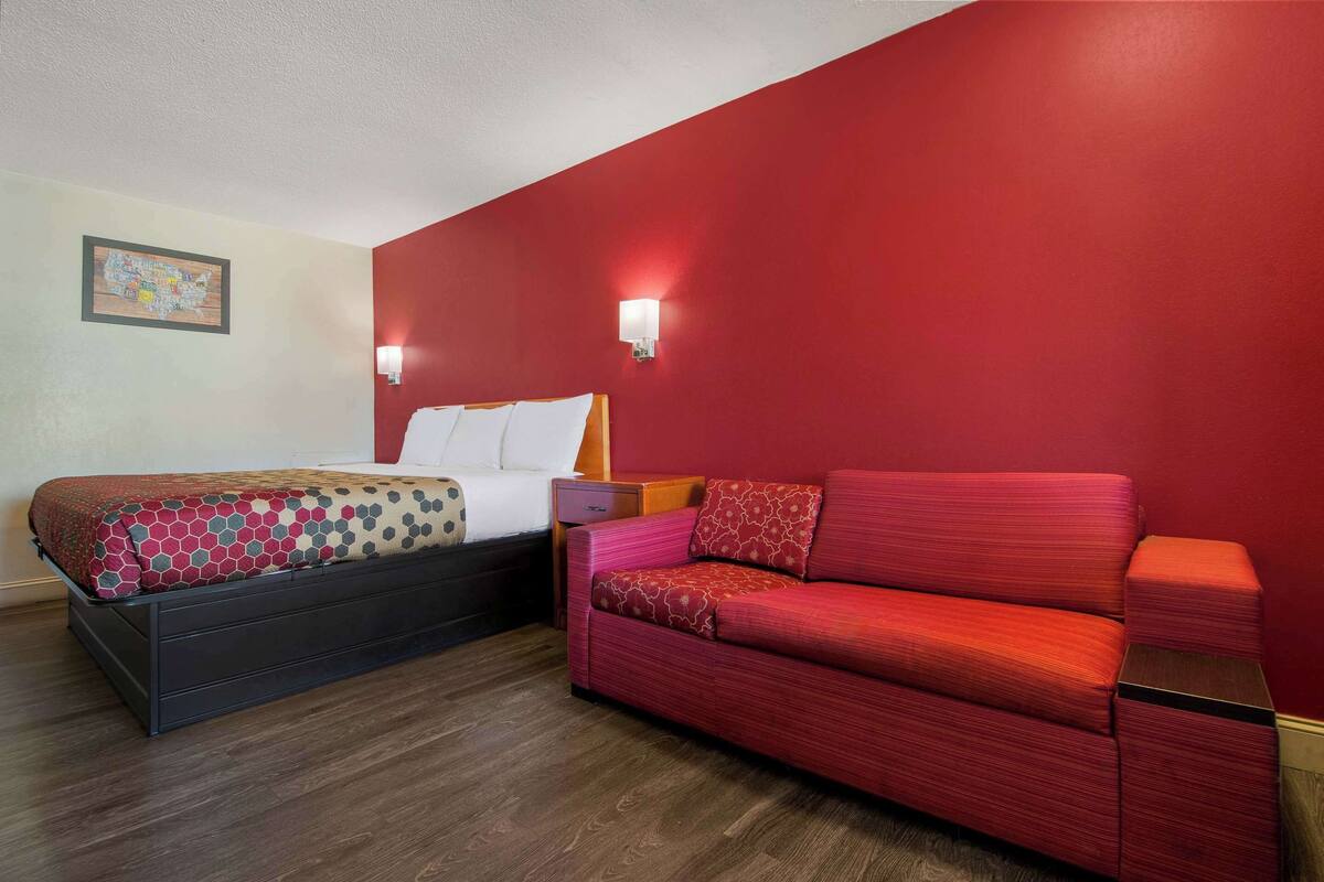 Ein Hotelzimmer mit einem Bett, einem roten Sofa und zwei Wandleuchten.