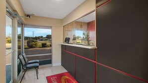A hotel reception area with a glass door leading outside, a reception desk with a digital screen, and a red carpet with the hotel's logo. - Econo Lodge Goldsboro Hwy 70 (Goldsboro)