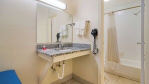 A bathroom with a sink, mirror, towel rack, and a shower area. - Econo Lodge Goldsboro Hwy 70 (Goldsboro)