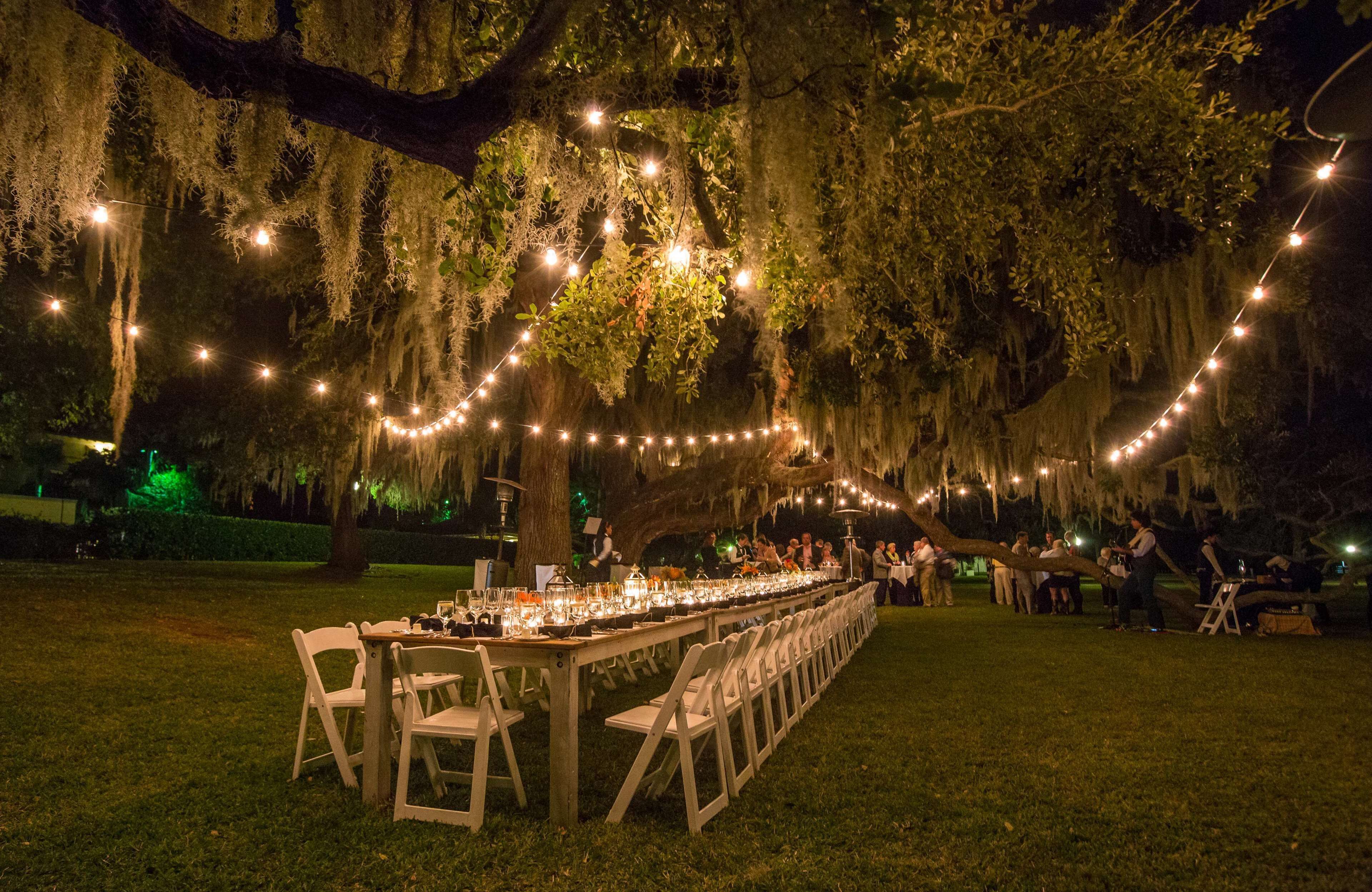 An outdoor dining area with string lights and a long table set for guests.