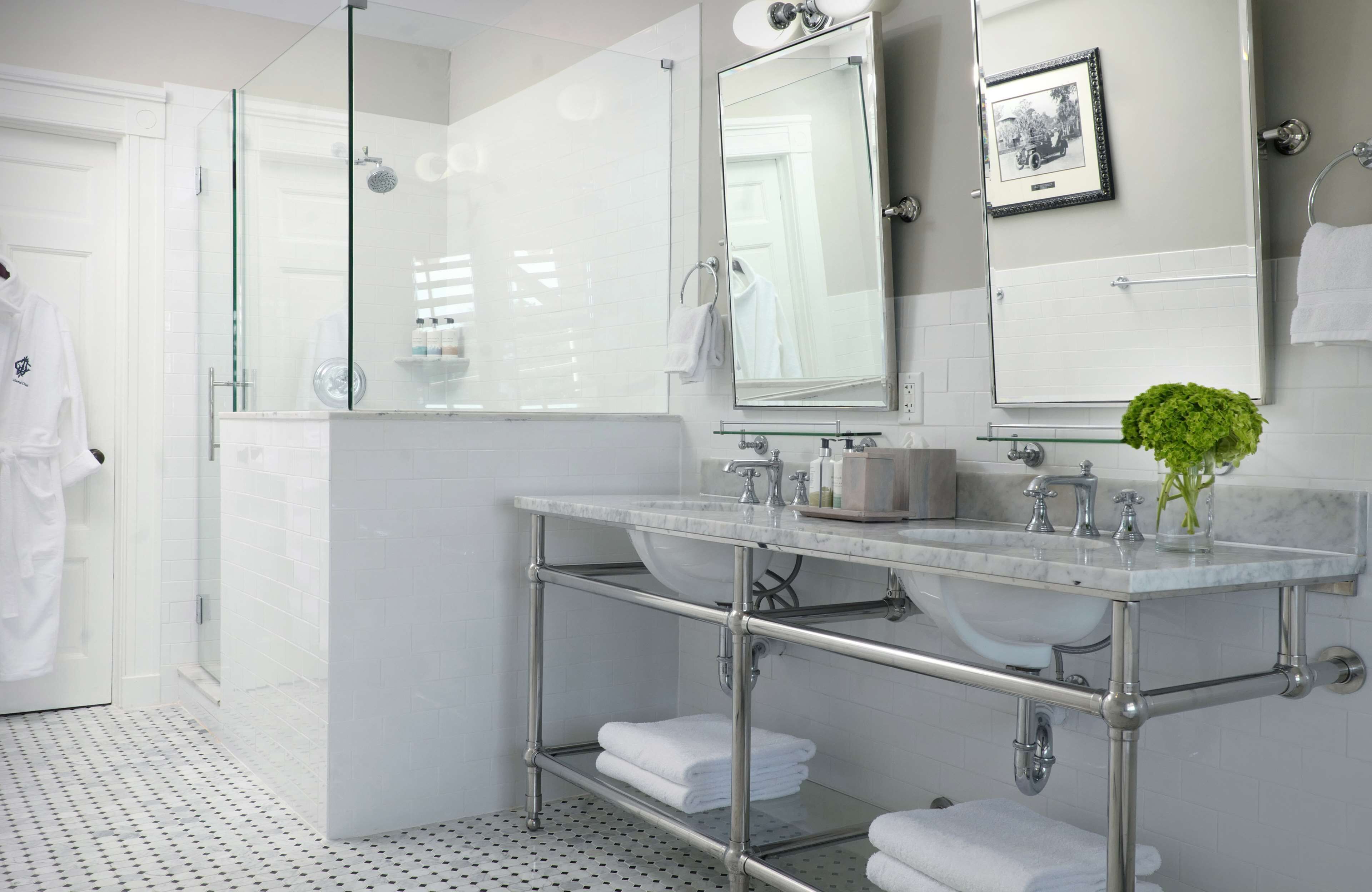 A modern bathroom with a glass shower enclosure, a large mirror, and a marble sink.