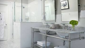 Un baño moderno con cabina de ducha de vidrio, un espejo grande y lavamanos de mármol.