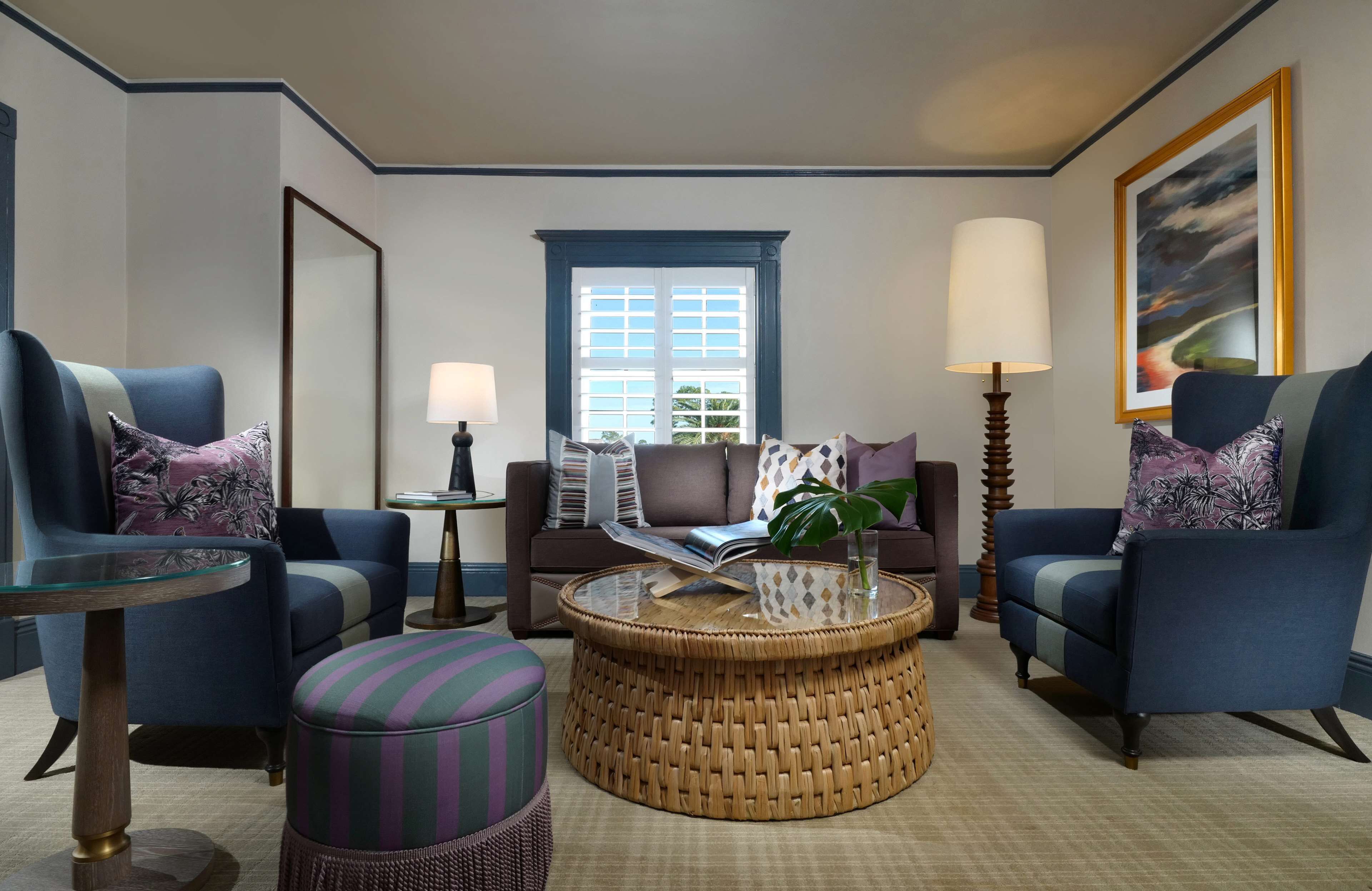 A modern living room with two armchairs, a sofa, a round coffee table, and a side table with a lamp.
