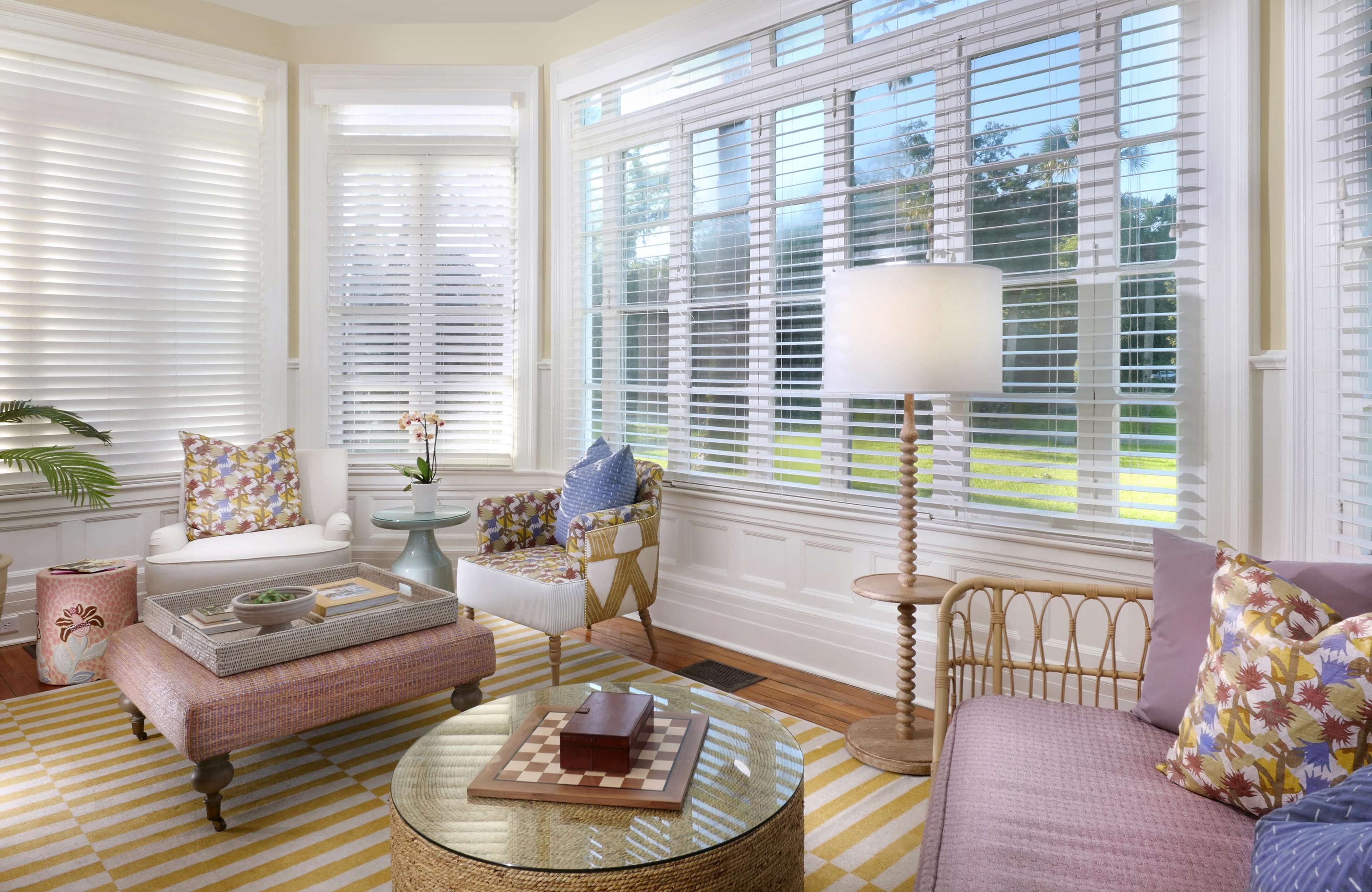 A well-lit living room with a large window, a round glass coffee table, a sofa, and a chair with a side table.
