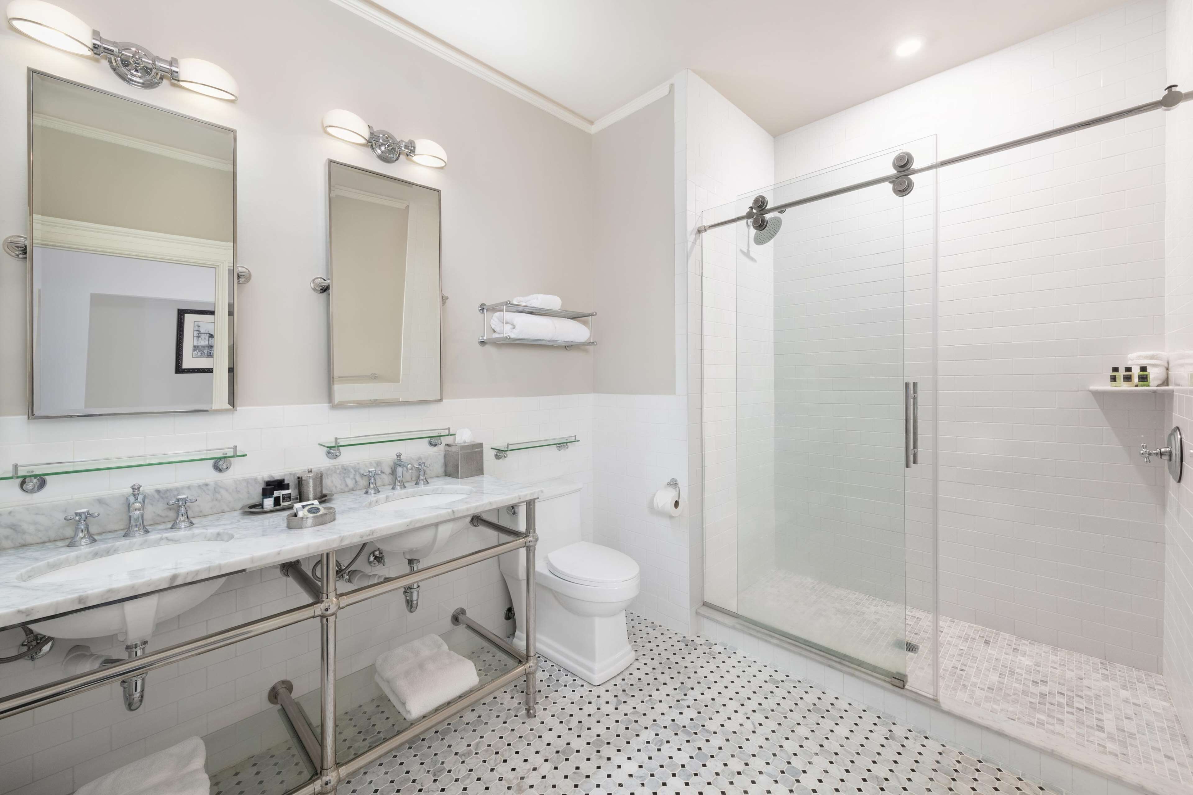Une salle de bain moderne dotée d’une douche à parois de verre, d’un meuble-lavabo à deux vasques et d’un grand miroir.