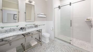 Une salle de bain moderne dotée d’une douche à parois de verre, d’un meuble-lavabo à deux vasques et d’un grand miroir.