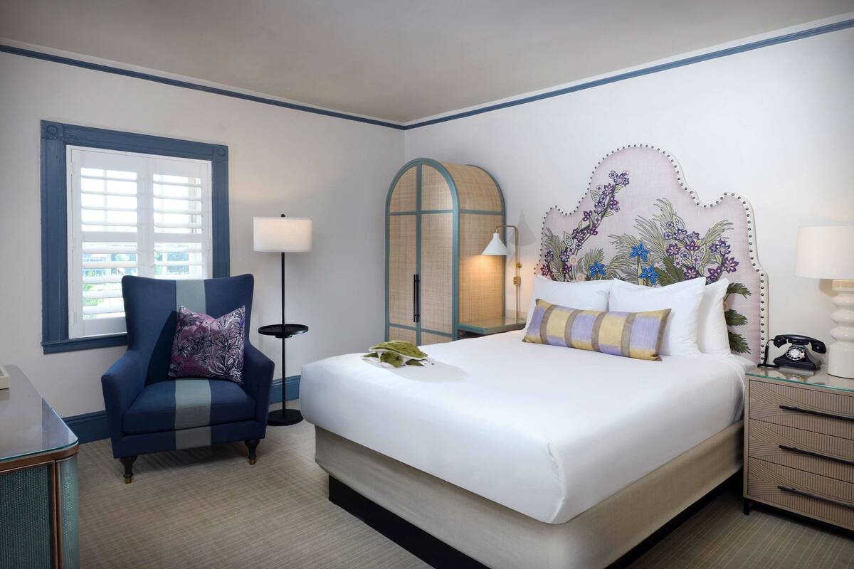 Une chambre d’hôtel avec un grand lit, une chaise, un bureau et une table de chevet.