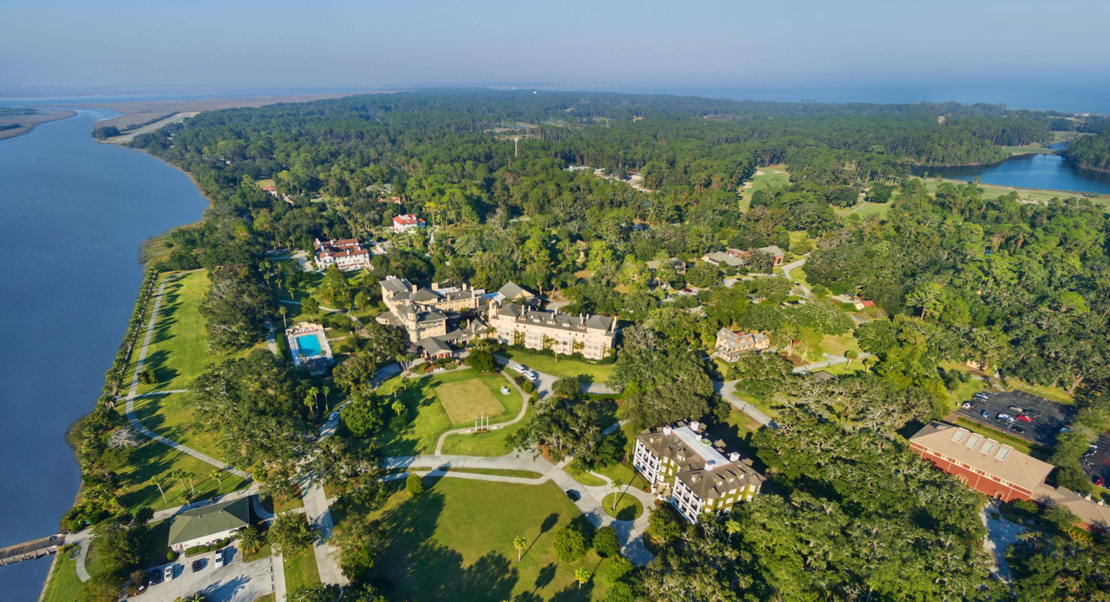 Vista aérea de una propiedad costera con varias construcciones, un campo de golf y una gran extensión de agua.