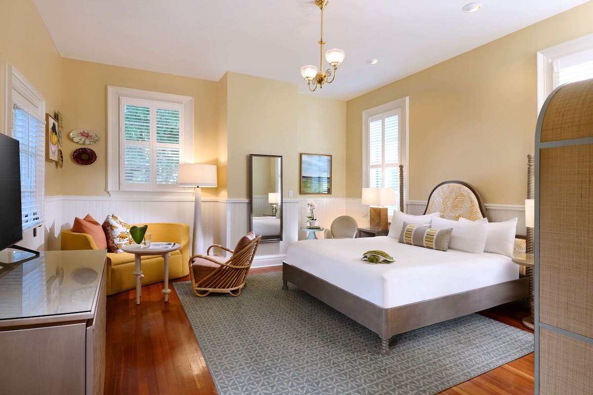 Une chambre d’hôtel comprenant un lit, un canapé, une chaise, un bureau et un téléviseur.