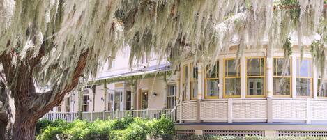 A historic building with a covered porch, large windows, and a well-maintained garden.