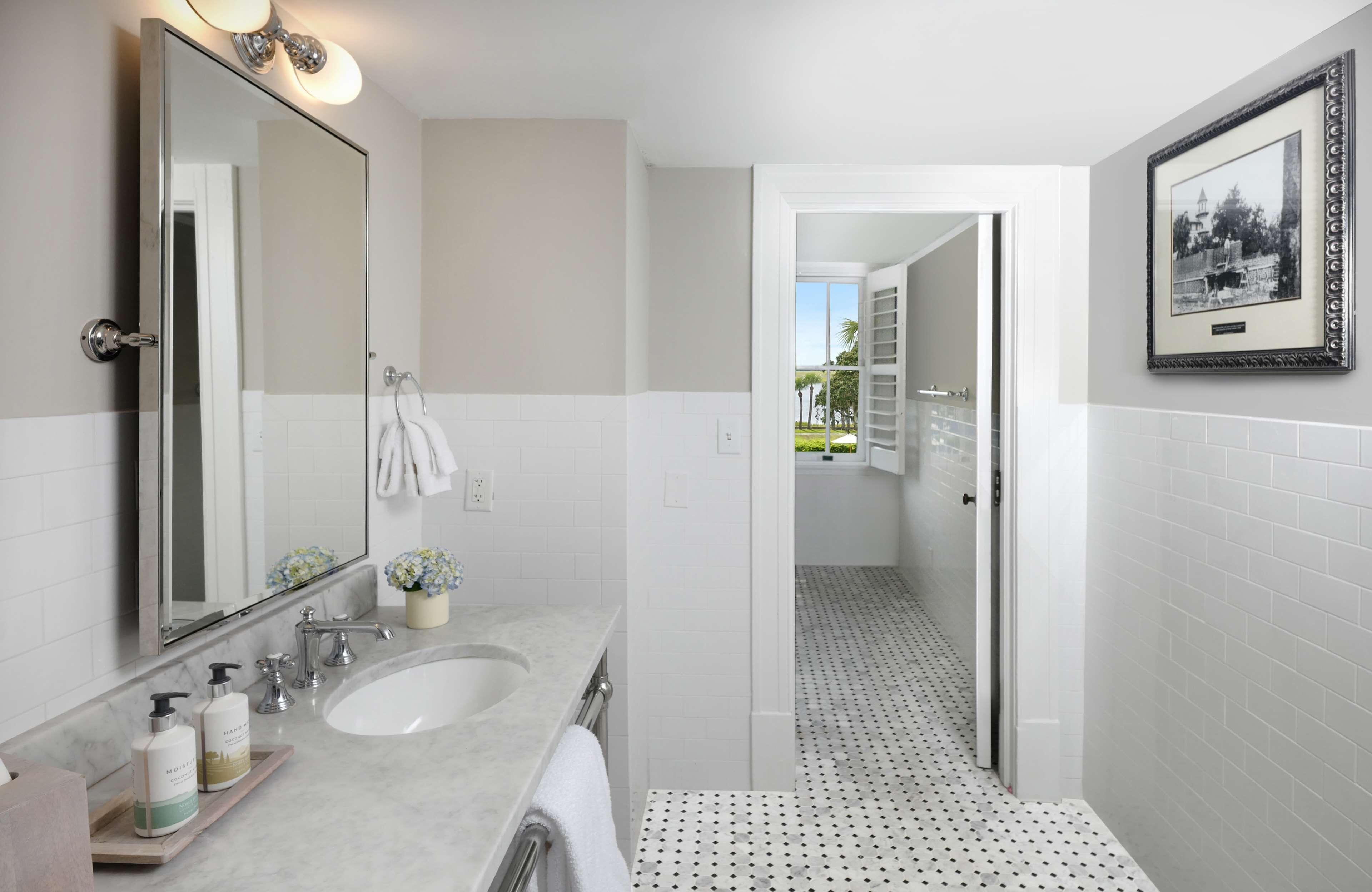 Un baño moderno con un espejo grande, dos lavamanos y suelo de baldosas.