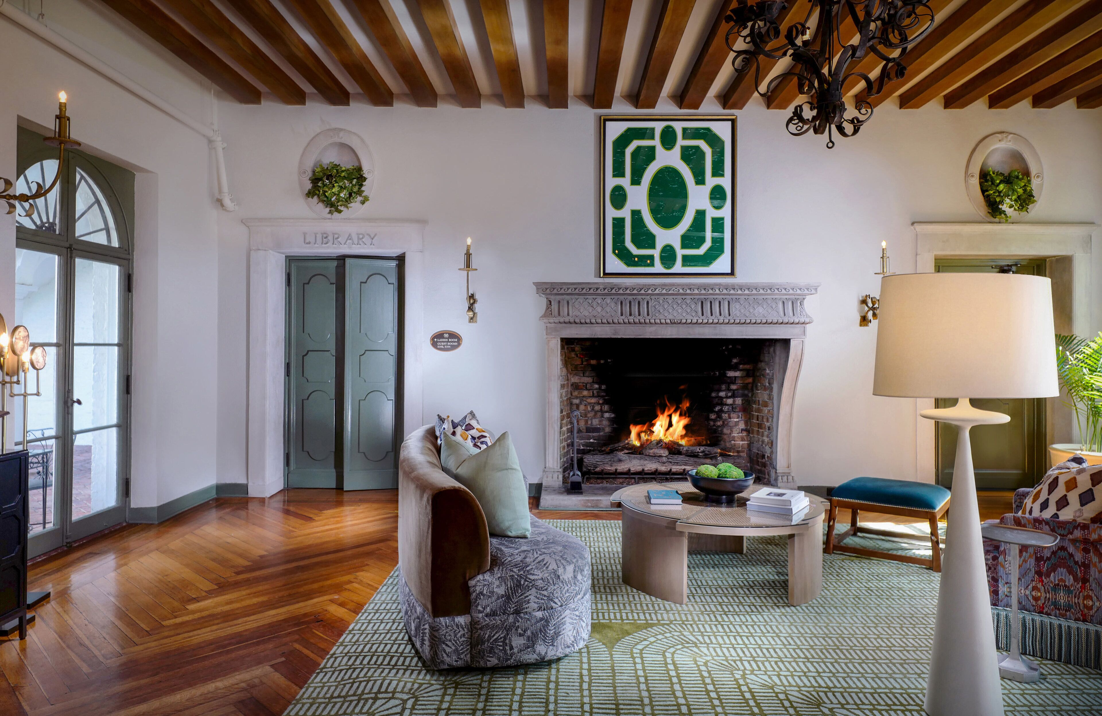 Una sala acogedora con chimenea, un espacio de estar confortable y una puerta que da a la biblioteca.