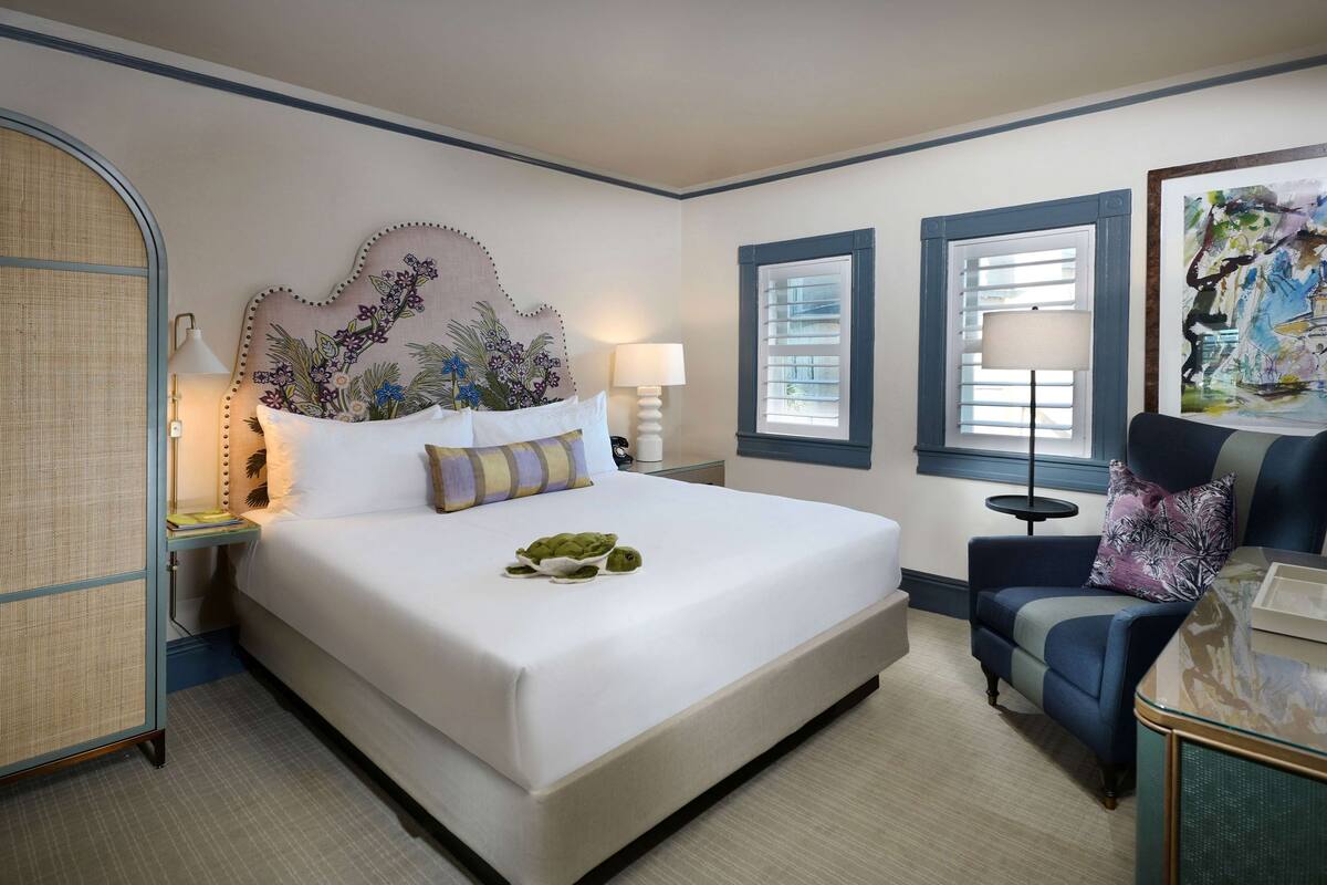 Une chambre d’hôtel bien aménagée, avec un grand lit, une table de chevet, une chaise et une tête de lit décorative.