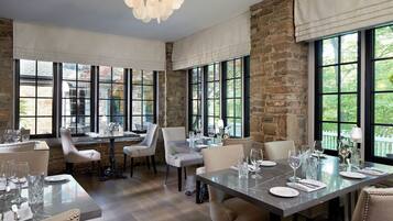 A dining area with a stone wall, large windows, and a chandelier.