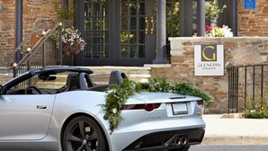 A silver convertible car parked in front of a building with a sign that reads "GLENEPIN INNASPA".
