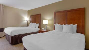 Quarto de hotel com duas camas, uma mesa de cabeceira com abajur e um telefone.